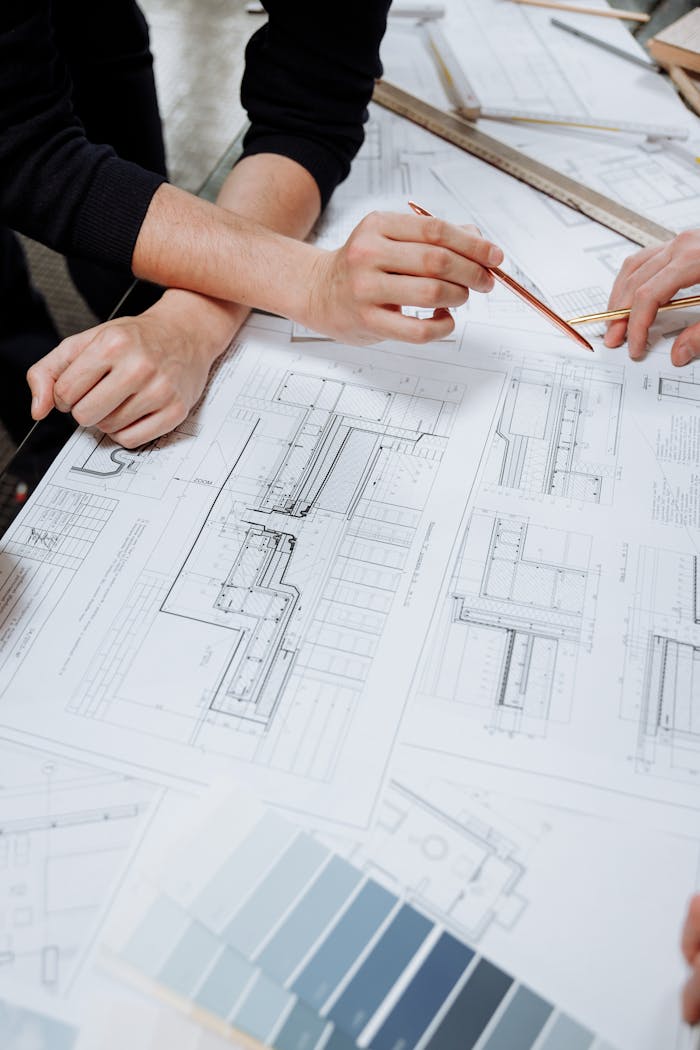 gallery-2 Architects discussing detailed blueprints and schematics at a table.