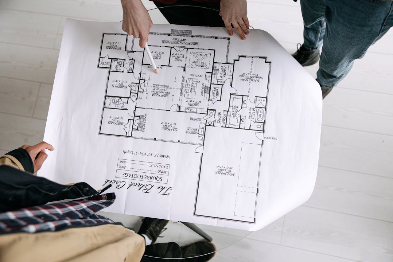 services-03 Two architects examining a detailed floor plan blueprint on a table indoors.